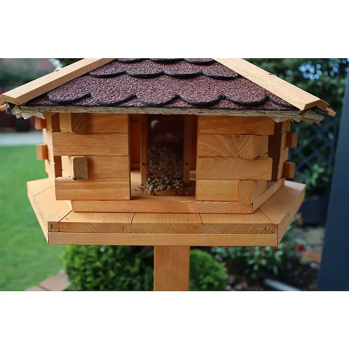 Promadino Vogelhaus Knusperhäuschen - Holz, Natur/Braun, Ausstattung: Ohne Vogelhausständer, Mit Silo - Nahaufnahme eines hölzernen Vogelhauses mit braunem Dach und Futter darin, um Vögel anzulocken und ihnen einen Unterschlupf zu bieten.