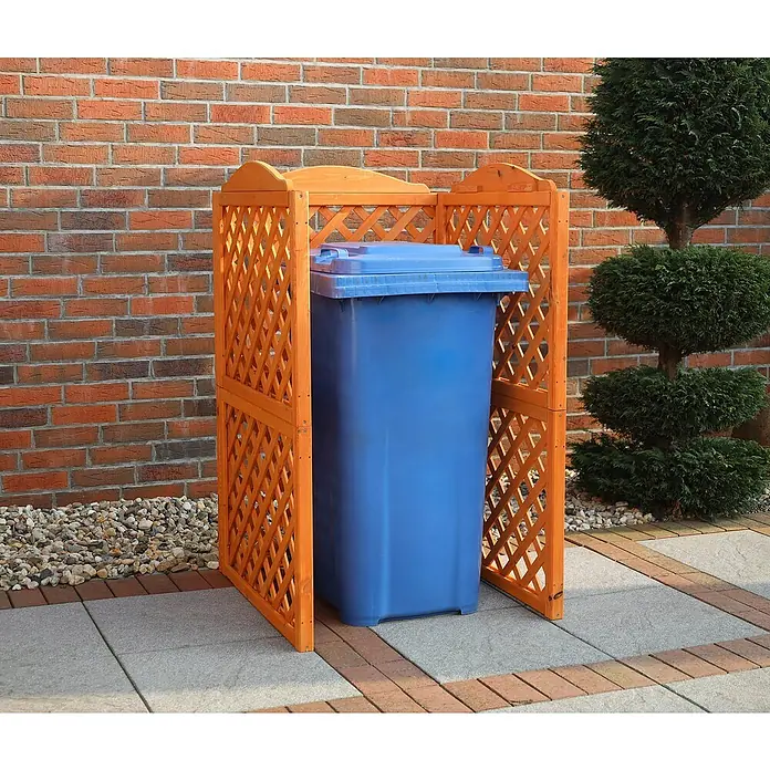 Promadino Mülltonnenbox Verkleidung Rex - 78,5 x 86,5 x 128 cm, Honigbraun - Der blaue Müllcontainer steht in einer Holzlattung vor einer Ziegelmauer und einem Zierbaum. Sieht ordentlich und aufgeräumt aus.
