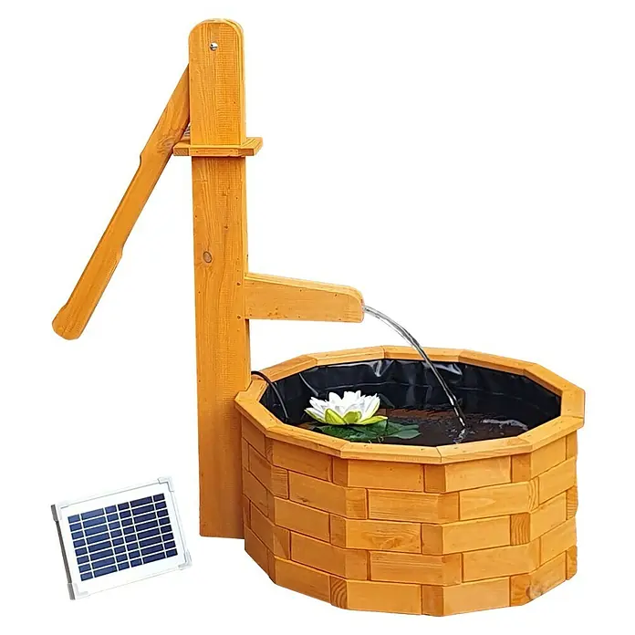 Promadino Standbrunnen - Ø x H: 64 x 101 cm, Solarpumpe - Eine rustikale Holzbrunnen-Dekoration mit Solarpanel, die einen Wasserstrahl in den Brunnen speit, umgeben von einer üppigen Landschaft.