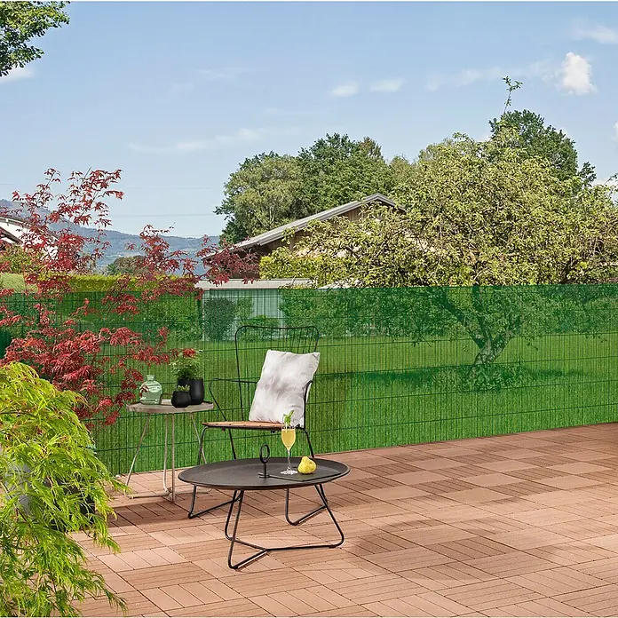 Windhager Drahtgitter - Grün, B x H: 3 x 1 m, Maschenweite: 5 x 5 mm - Ein einladender Gartenbereich mit einem stilvollen Metalltisch und Stuhl, der zum Verweilen einlädt. Der grüne Sichtschutz bietet Privatsphäre.