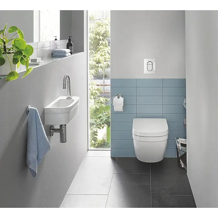 Grohe Kaltwasser-Standventil Universal - C-Auslauf, Chrom, Glänzend - Das Bild zeigt ein modernes Badezimmer mit einer weißen Toilette und einem kleinen Waschbecken an der Wand. Das blaue Fliesendesign ist ein Hingucker.