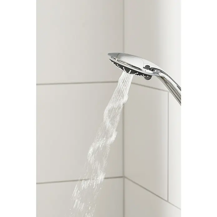 Grohe Vitalio Joy Duschsystem 260 - Mit Thermostatarmatur, Lochabstand: 100,5 cm, Anzahl Strahlarten: 3 Stk., Chrom - Nahaufnahme eines Duschkopfes aus Chrom, aus dem Wasserstrahlen sprudeln, vor einem Hintergrund aus weißen Fliesen.