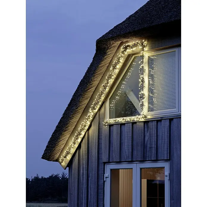 Tween Light Cadena de luces LED - Para exterior, Largo: 8,15 m, 768 ud., Funcionamiento en red, Color de luz: Blanco cálido - Esta imagen muestra una casa con una ventana a dos aguas decorada con luces, creando un ambiente acogedor y festivo.