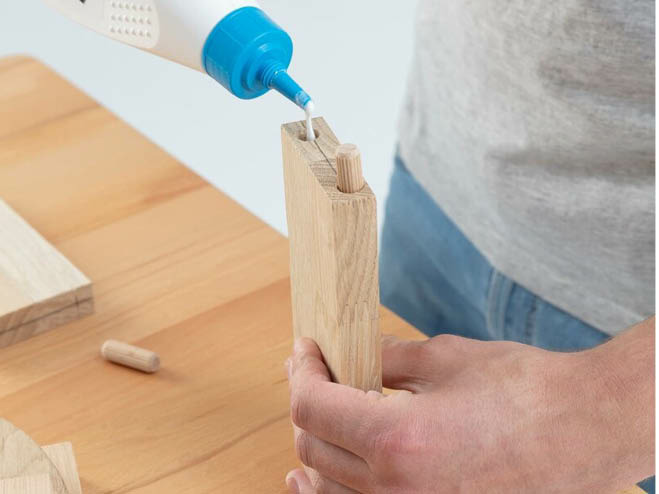 Holzleim wird in eine Bohrung eingefüllt, damit der Dübel hält