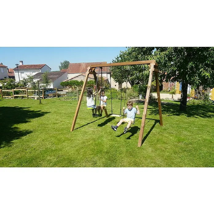 Soulet Schaukel Gautier - B x L: 207 x 240 cm, Holz - Eine hölzerne Schaukel mit drei Kindern darauf in einem Garten, mit Häusern im Hintergrund.