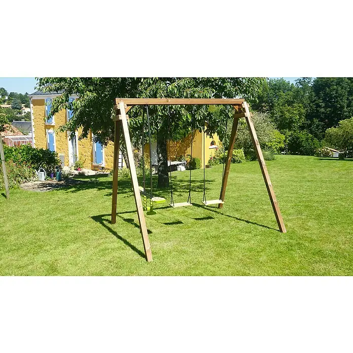 Soulet Schaukel Gautier - B x L: 207 x 240 cm, Holz - Eine hölzerne Kinderschaukel steht auf einem grünen Rasen vor einem Haus, umgeben von Bäumen. Perfekt für Outdoor-Spielspaß!