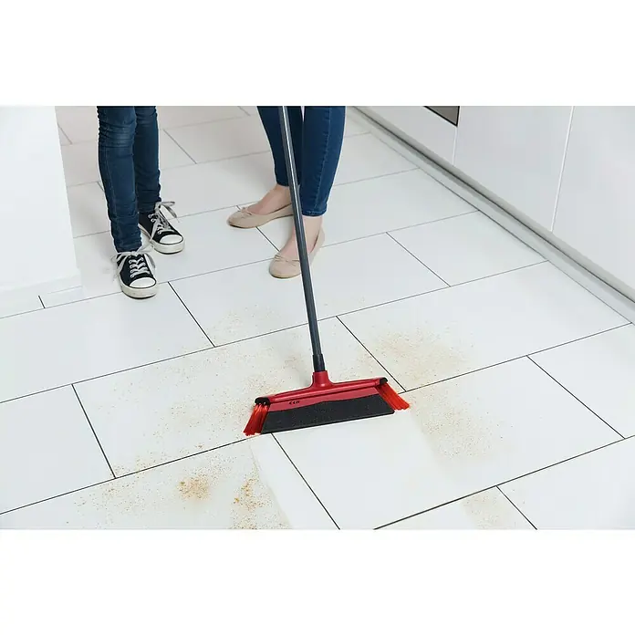 Vileda Superfeger Straßenbesen Antistaub Duactiva - Mit Teleskopstiel, Material Borsten: Synthetik, Breite Besen: 35 cm - Eine rote Kehrmaschine mit einem grauen Griff wird verwendet, um Krümel und Staub von einem weißen Fliesenboden in einer Küche zu entfernen.