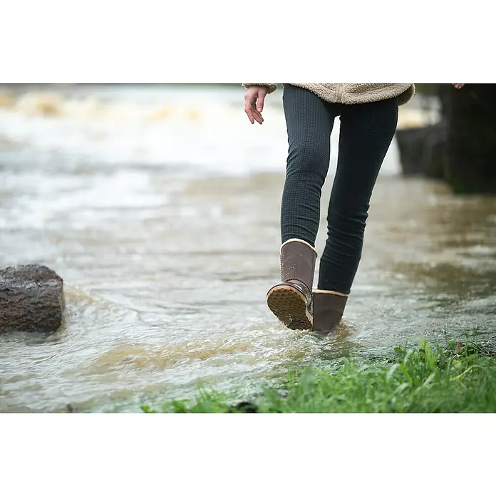 Black Fox Winterstiefel Cheyennetoo - Schuhgröße: 42, Dunkelbraun - Braune Winterstiefel mit hellem Futter und strukturierter Sohle, getragen von einer Person, die durch seichtes Wasser geht.