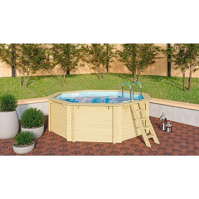 Karibu Holz-Pool Orlando Größe 1 - L x B x H: 400 x 400 x 124 cm, Naturbraun, 11.000 l, Ohne Poolterrasse - Ein hölzernes, achteckiges Schwimmbecken mit Leiter steht auf einer gepflasterten Terrasse.
