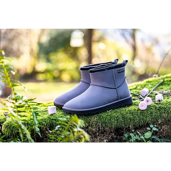 Black Fox Winterstiefel flach Cheyennetoo - Schuhgröße: 38, Grau - Ein Paar graue Blackfox-Stiefeletten mit schwarzer Sohle stehen auf einem moosbedeckten Untergrund, umgeben von Eibischbonbons.