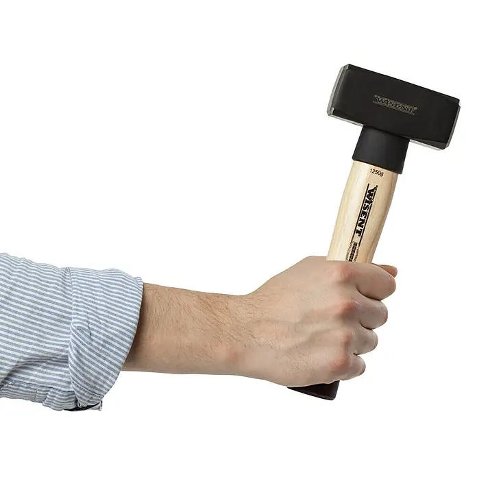 Wisent Mazo - 1.250 g, Acero - Primer plano de un martillo Wisent con mango de madera, sujetado por una mano. Herramienta para trabajos pesados.
