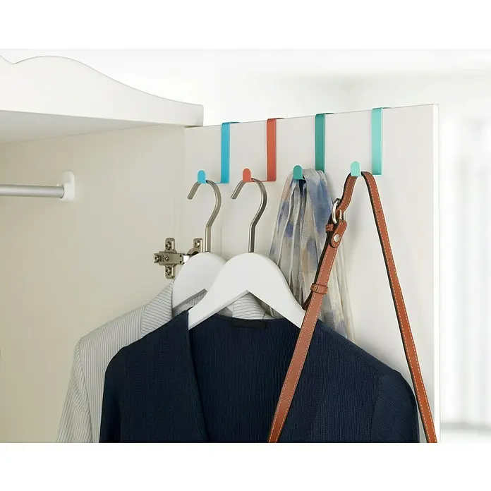 Wenko Colgador de baño Sobrepuerta - Multicolor, 4 ud. - Un primer plano de ganchos de puerta de colores con ropa y un bolso colgados en un armario blanco. Solución de almacenamiento práctica.