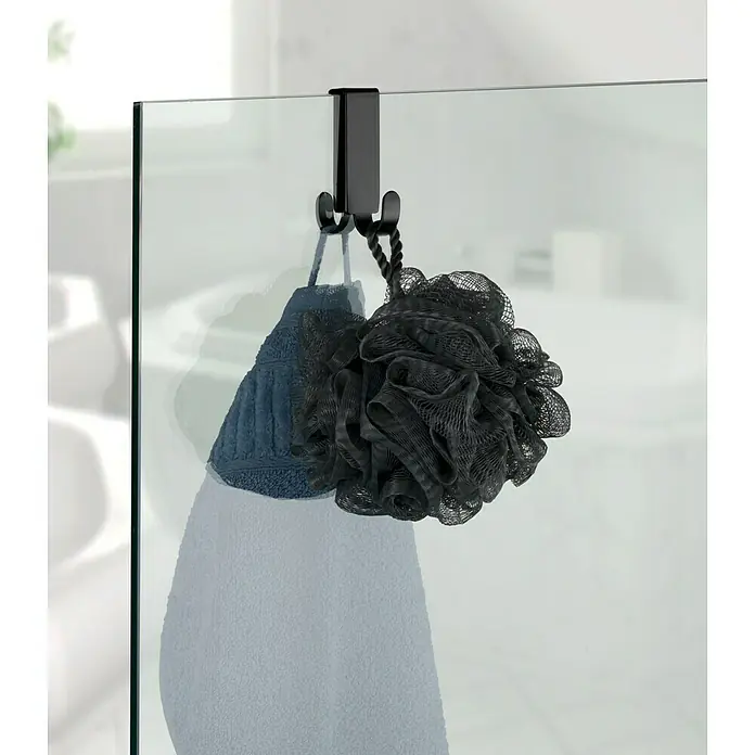Wenko Colgador de baño Vieste - L x Al: 5,5 x 7 cm, Número de ganchos: 2 ud., Negro - Gancho de ducha con una toalla azul y una esponja de baño negra colgadas en una puerta de vidrio.