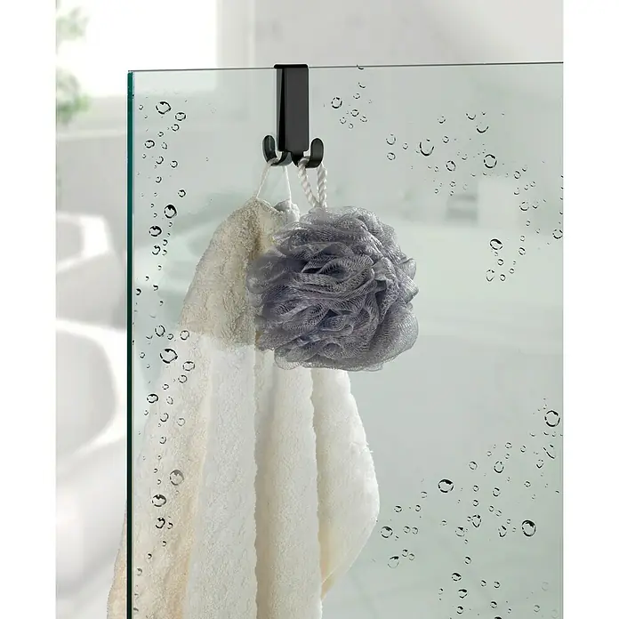 Wenko Colgador de baño Vieste - L x Al: 5,5 x 7 cm, Número de ganchos: 2 ud., Negro - Gancho para puerta de ducha con toalla y esponja de baño. El gancho es negro y cuelga de una mampara de cristal con gotas de agua.