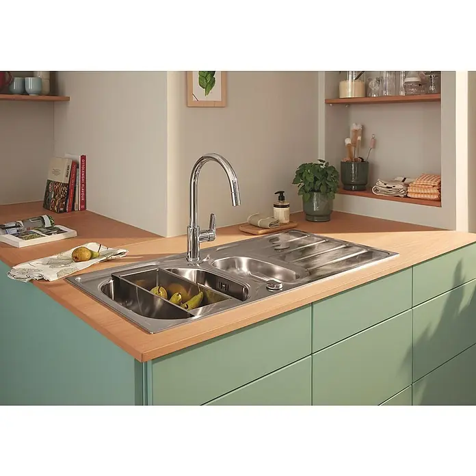 Grohe Grifo de cocina Start Edge - Cromo, Brillante - Fregadero de acero inoxidable con escurridor y grifo, lleno de peras, en una cocina moderna con armarios verde claro y encimera de madera.