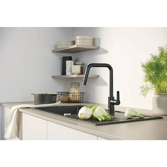 Grohe Grifo de cocina Start - Negro, Mate - Elegante grifo de cocina negro con verduras sobre una tabla de cortar que descansa sobre un fregadero moderno.
