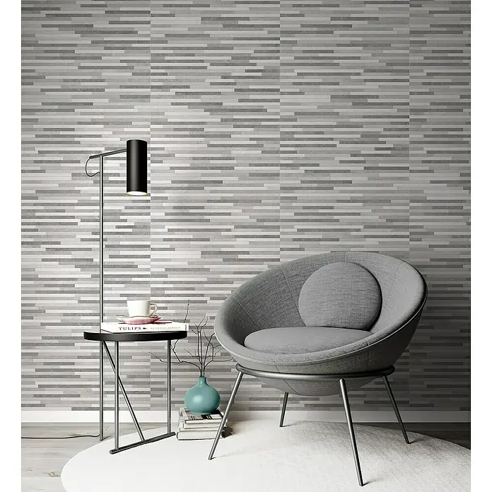 Revestimiento de pared Cantera Mureto - 33 x 55 cm, Gris, Mate - Una moderna escena interior en tonos grises con una silla circular, una lámpara y una mesa auxiliar contra una pared con motivos horizontales.