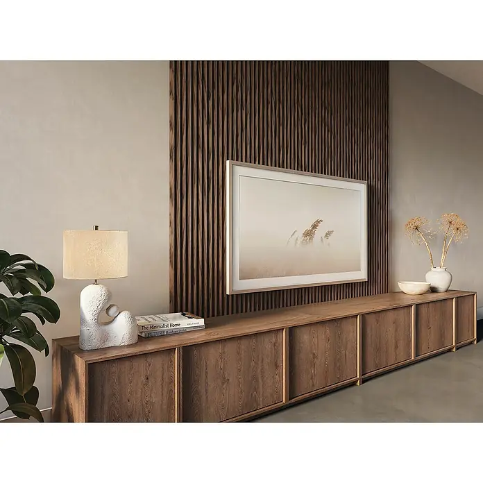 CanDo Akustikpaneel Curve - Walnuss Uni, 2.600 x 300 x 19 mm, 2 Stk. - Elegantes Wohnzimmer mit The Frame-Fernseher an einer Akzentwand, ergänzt durch eine lange Holzkommode, eine Lampe und Dekorationen.