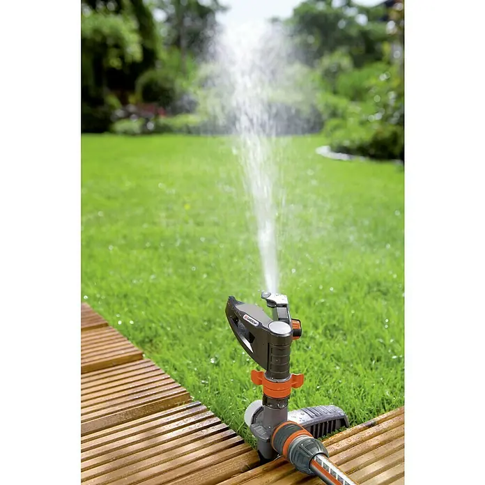 Gardena Comfort Kreisregner - Max. Regnerfläche: 490 m² - Rasensprenger von Gardena in Aktion, der Wasser auf eine grüne Rasenfläche sprüht und für Bewässerung sorgt.