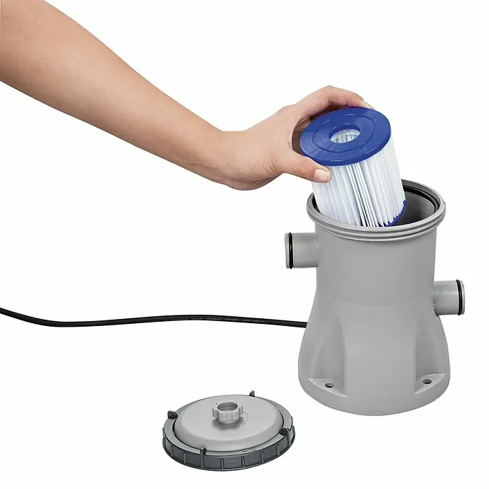 Bestway Lay-Z-Spa Eisbad Glacial Dip - L x B x H: 152 x 92 x 71 cm - Eine Person setzt einen blauen Filter in ein graues Schwimmbeckenfiltersystem ein, wobei der Deckel daneben liegt.