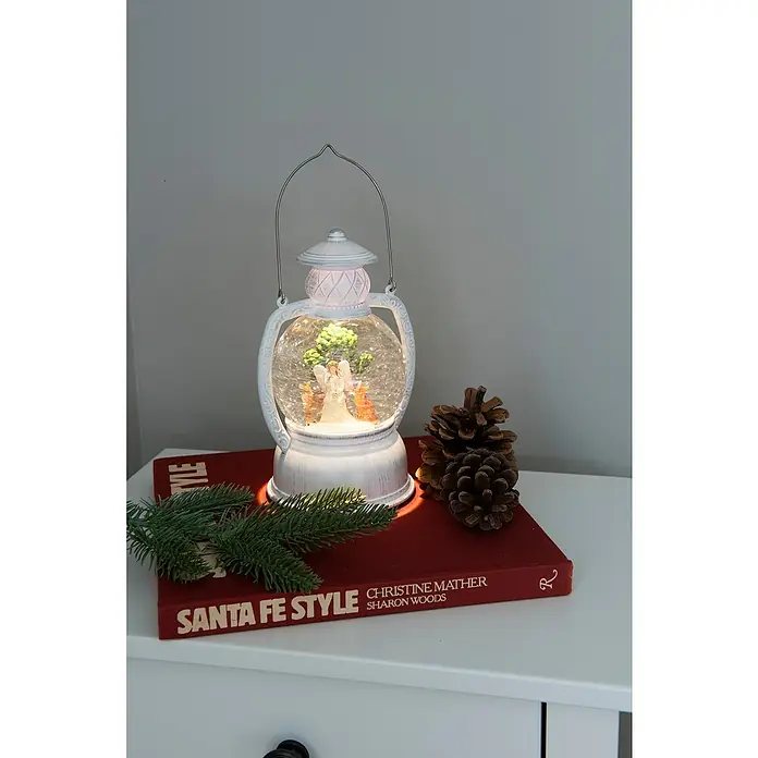 Konstsmide LED-Schneelaterne - Innen, 11,2 x 12,4 x 20 cm, Batteriebetrieben - Beleuchtete weiße Laternen-Schneekugel mit Engel und Rehen, auf einem roten Buch mit Tannenzapfen und Tannenzweigen.