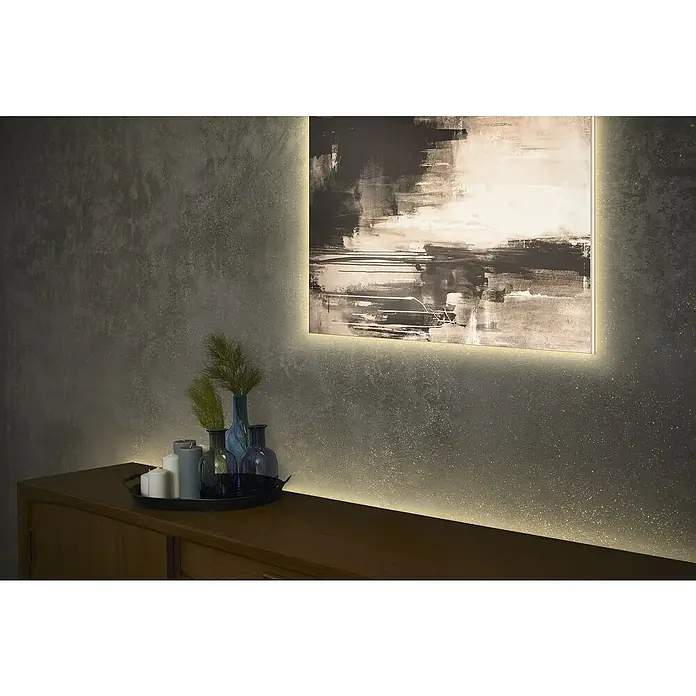 Ledvance LED-Stripes Flex Cob - Länge: 200 cm, Warmweiß, 3,3 W - Ambiente warmweiße LED-Streifenbeleuchtung hinter einem abstrakten Gemälde und einem Holzsideboard.