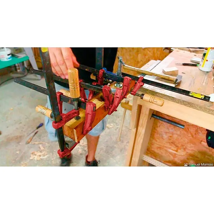 Piher Sargento MM-30 - Anchura de sujeción: 300 mm, Fuerza de tensión: 4.000 N, Apertura máxima: 70 mm - Primer plano de herramientas de carpintería que aseguran una construcción de madera con abrazaderas rojas.
