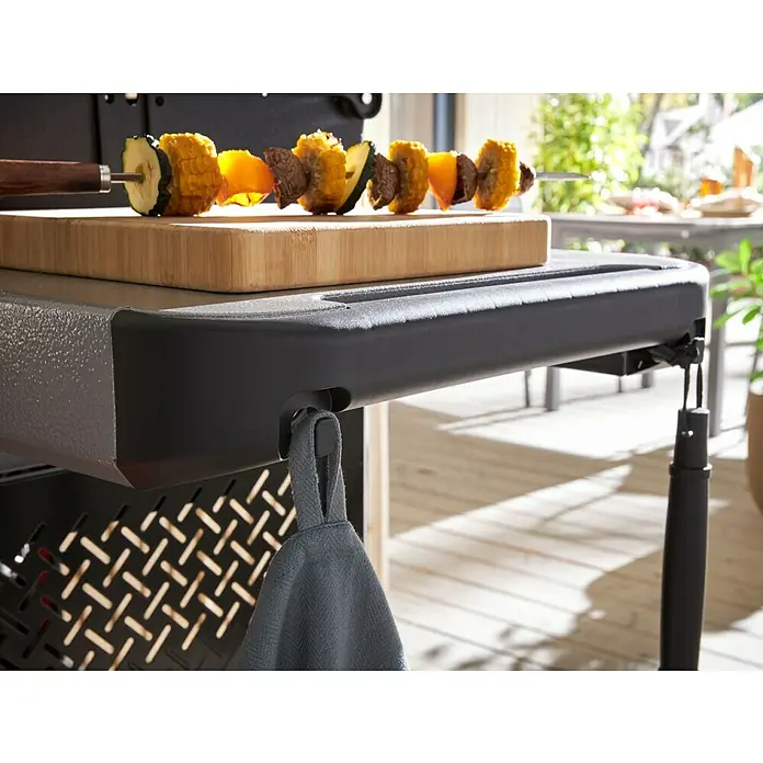 Weber Gasgrill Spirit E-210 - Grillfläche (B x T): 52 x 44 cm, 7,8 kW, Anzahl Brenner: 2 Stk. - Nahaufnahme eines Grills mit Spieß, Schneidebrett und einem grauen Handtuch.