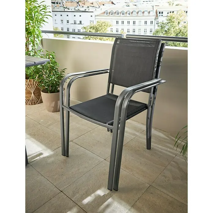Stapelstuhl - Stahl, Textil, Stapelbar, Night-Grey, B x T x H: 56 x 66 x 86 cm - Nahaufnahme eines grauen Gartenstuhls mit Armlehnen auf einem Balkon, der zum Entspannen im Freien einlädt.