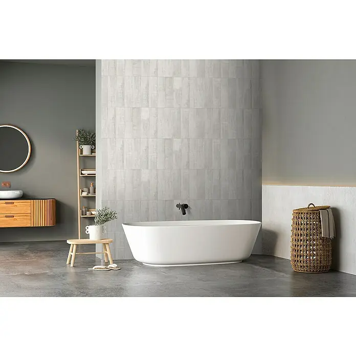 Panel de pared Barideck microcemento vertical - 9 ud., 78 x 39 cm - Elegante baño con bañera exenta, azulejos grises y detalles de madera clara, creando un ambiente relajante.