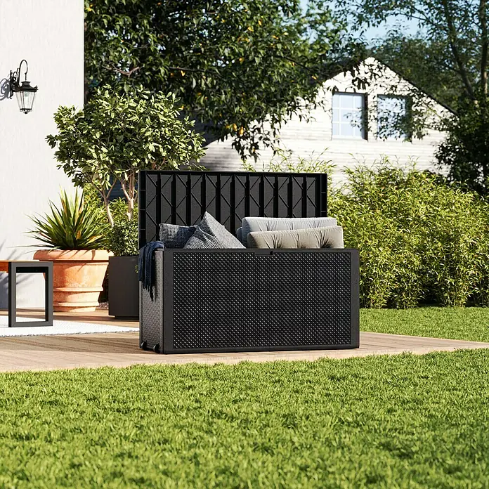 Keter Garten-Aufbewahrungsbox Emily - L x B x H: 117,8 x 44,6 x 58 cm, Graphite, Kunststoff - Schwarze Gartenbox mit Kissen auf einer Holzterrasse. Die Box bietet Stauraum für Gartenutensilien und Polster.