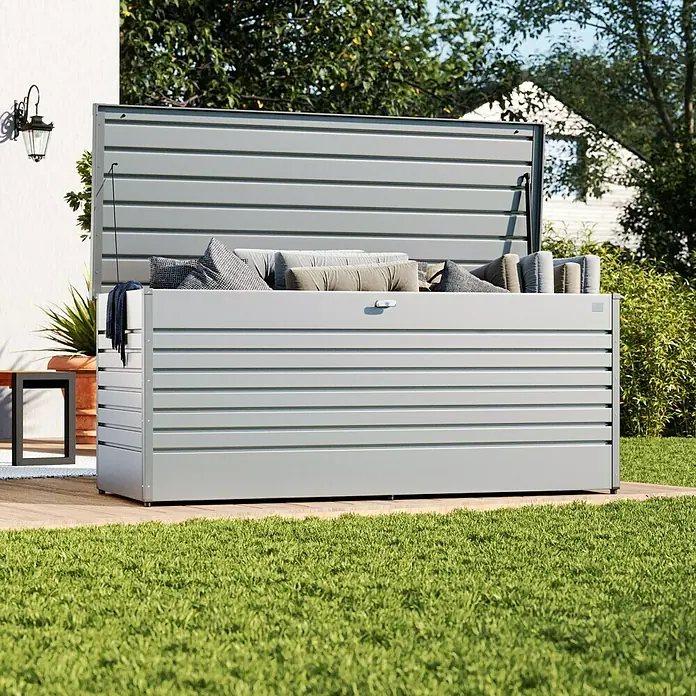 Biohort FreizeitBox Gartenbox 200 - L x B x H: 79 x 201 x 83 cm, Stahl, Silber Metallic - Graue Outdoor-Aufbewahrungsbox mit horizontalen Lamellen und Kissen, die im Garten auf dem Rasen steht.