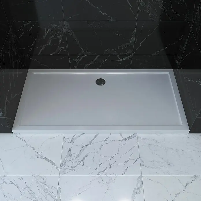 Aurlane Duschwanne Pure - L x B: 140 x 90 cm, Sanitäracryl, Weiß, Rechteckig - Weißes rechteckiges Duschbecken mit silbernem Abfluss, installiert in einem modernen Bad mit schwarzen und weißen Marmorfliesen.