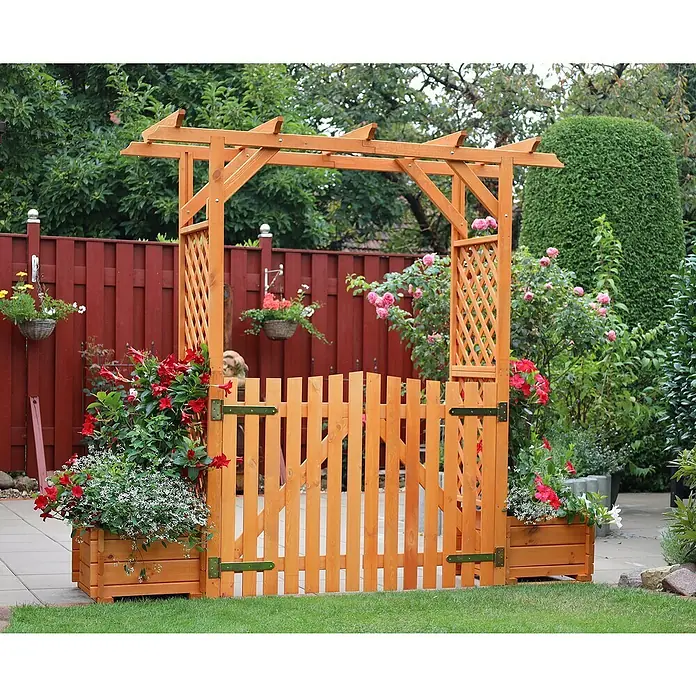 Promadino Pergola Bamberg - Höhe: 208 cm, Ausführung: Tür & Pflanzkasten - Ein Holzgartenbogen mit einem kleinen Holzzaun. Der Gartenbogen ist mit Blumenkästen und hängenden Pflanzen dekoriert.