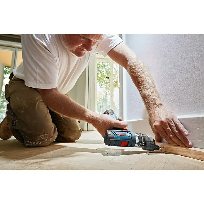 Bosch Professional Accesorio excéntrico GFA 12-E - Específico para: Atornillador de batería Bosch Professional GSR 12V-15 - Un artesano sujeta una tira de madera a una pared utilizando un destornillador inalámbrico Bosch. La herramienta es compacta e ideal para trabajos de precisión.