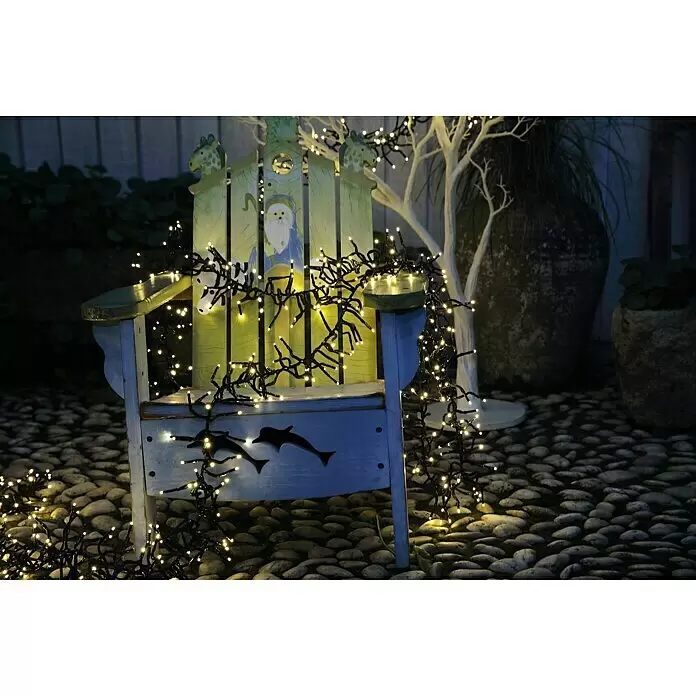Tween Light LED-Clusterlichterkette - Außen, Länge: 12,4 m, 1.000 Stk., Netzbetrieben, Lichtfarbe: Warmweiß - Warmweiße Lichterkette über einem blau-grünen Holzstuhl, der Santa- und Delfindetails beleuchtet.