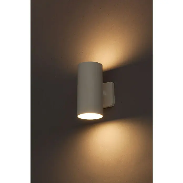 Starlux Akku-Wandleuchte Avio - 2,6 W, 7,1 x 5,3 x 11 cm, IP44, Matt Weiß - Nahaufnahme einer zylindrischen, weißen Wandleuchte, die warmes Licht nach oben und unten abstrahlt und eine gemütliche Atmosphäre erzeugt.