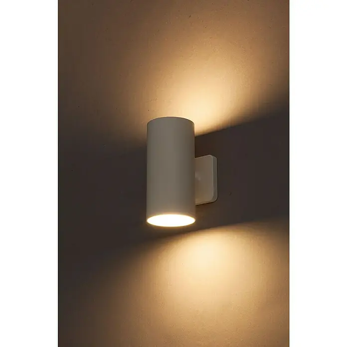 Starlux Akku-Wandleuchte Avio - 2,6 W, 7,1 x 5,3 x 11 cm, IP44, Matt Weiß - Nahaufnahme einer modernen, zylindrischen Wandleuchte, die ein warmes, nach oben und unten gerichtetes Licht abgibt.
