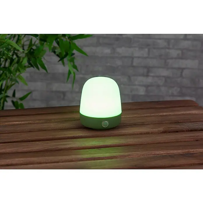 Starlux Akku-Tischleuchte Mini - L x B x H: 10 x 10 x 12 cm, Matcha Green, RGBW, 0,3 W, IP44 - Das Bild zeigt eine LED-Tischleuchte in Grün und Weiß auf einem Holztisch, ideal für gemütliche Abende.
