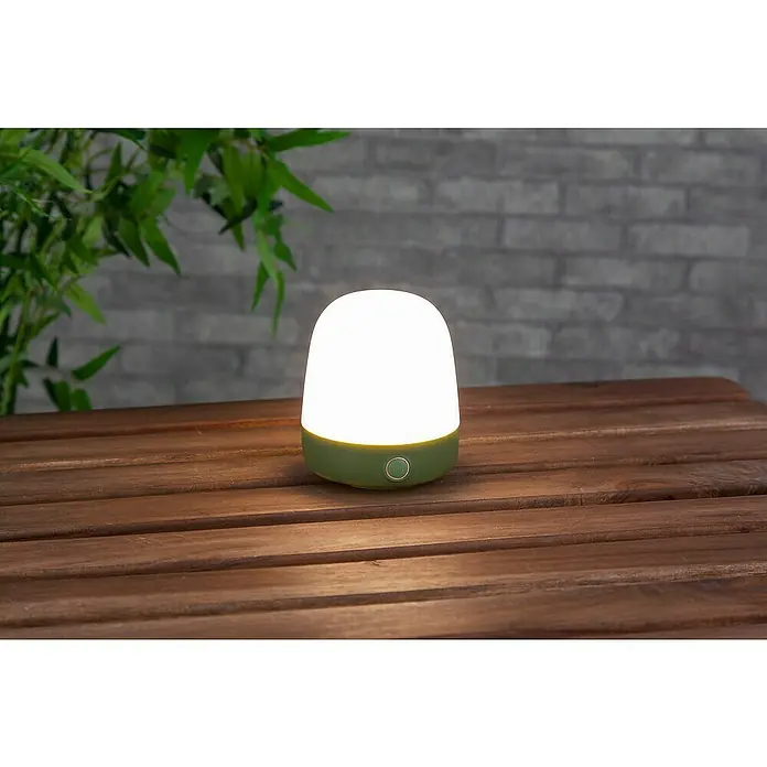 Starlux Akku-Tischleuchte Mini - L x B x H: 10 x 10 x 12 cm, Matcha Green, RGBW, 0,3 W, IP44 - Eine sanft leuchtende, grüne Tischleuchte auf einem Holztisch, ideal für gemütliche Abende im Freien.