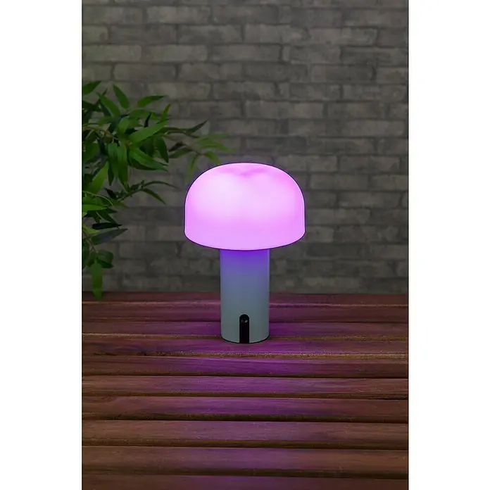 Starlux Akku-Tischleuchte Pilz - 1 W, L x B x H: 22 x 15 x 15 cm, RGBW, Grün - Eine pilzförmige Lampe mit einem lila leuchtenden Lampenschirm, die auf einem rustikalen Holztisch steht, ideal für stimmungsvolle Beleuchtung.