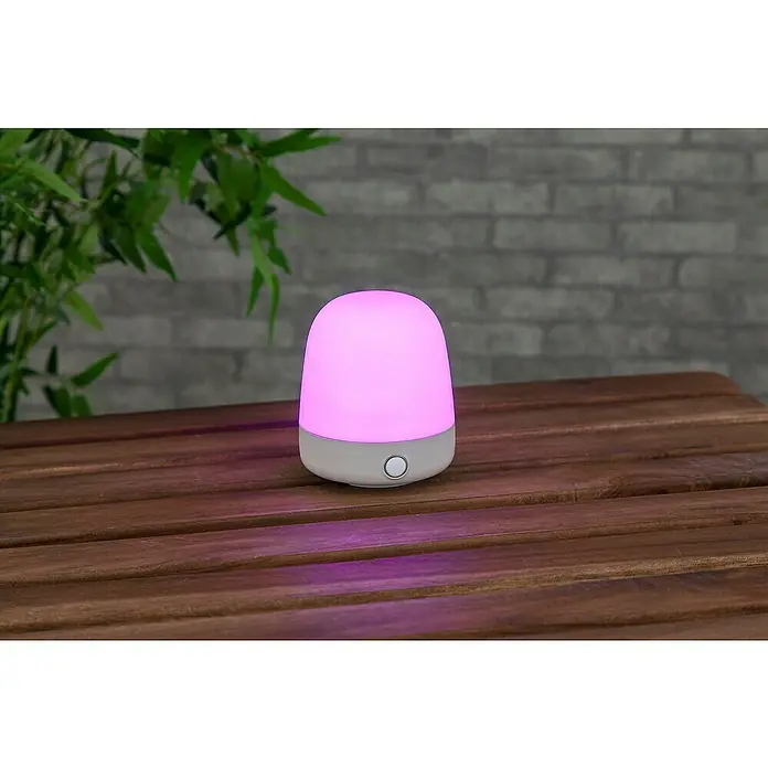 Starlux Akku-Tischleuchte Mini - L x B x H: 10 x 10 x 12 cm, Beige, RGBW, 0,3 W, IP44 - Nahaufnahme einer leuchtenden rosa Lampe mit beruhigendem Licht auf einem Holztisch, ideal als Nachtlicht oder zur Stimmungsaufhellung.