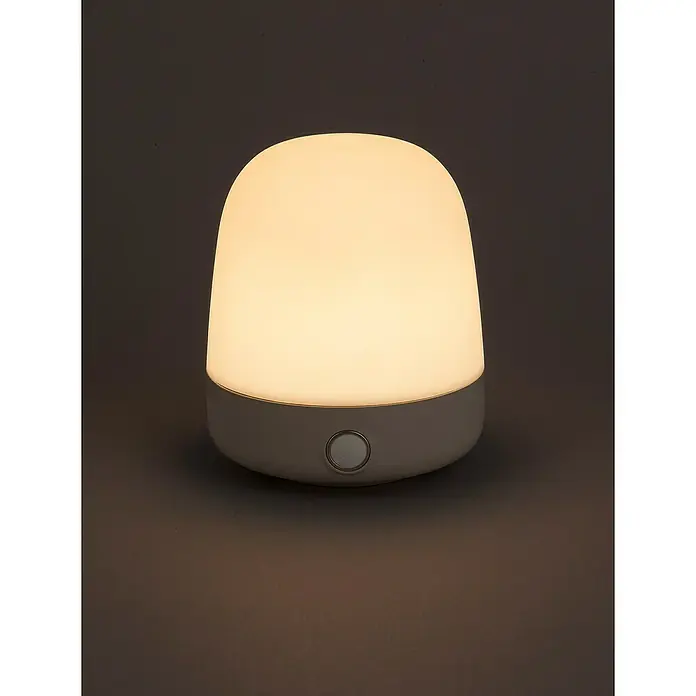 Starlux Akku-Tischleuchte Mini - L x B x H: 10 x 10 x 12 cm, Beige, RGBW, 0,3 W, IP44 - Nahaufnahme einer Nachttischlampe mit sanftem, warmem Licht, die eine beruhigende Atmosphäre schafft.\n