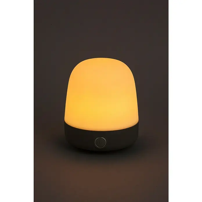 Starlux Akku-Tischleuchte Mini - L x B x H: 10 x 10 x 12 cm, Light Grey, RGBW, 0,3 W, IP44 - Nahaufnahme einer warm leuchtenden, kabellosen Tischleuchte mit einer grauen Basis und einem runden Knopf zum Einschalten.