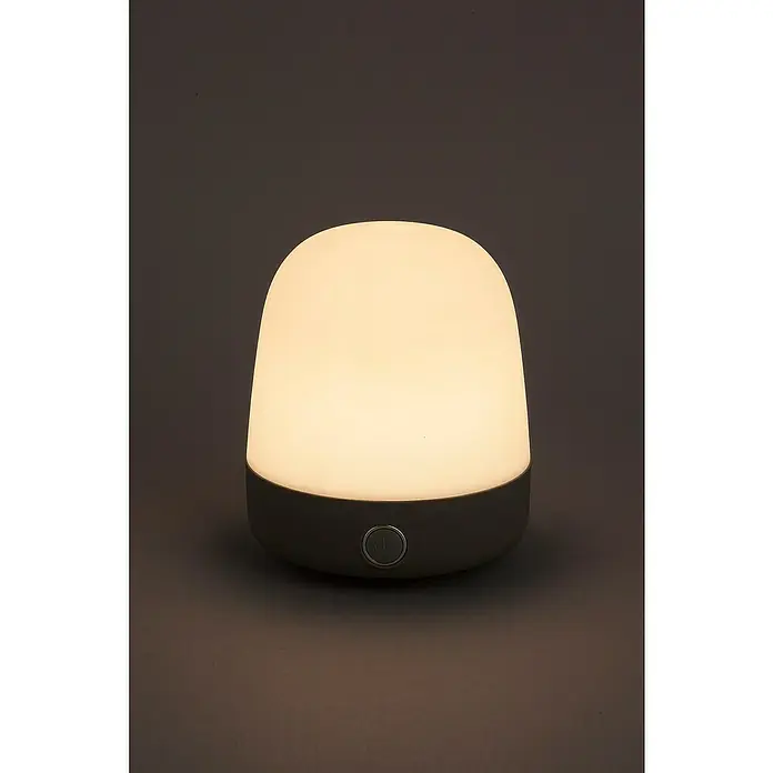 Starlux Akku-Tischleuchte Mini - L x B x H: 10 x 10 x 12 cm, Light Grey, RGBW, 0,3 W, IP44 - Das Bild zeigt eine Nachttischlampe mit warmem Licht und einem Knopf für die Bedienung, die eine gemütliche Atmosphäre schafft.