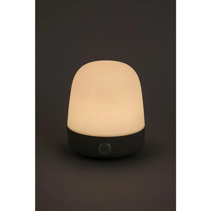 Starlux Akku-Tischleuchte Mini - L x B x H: 10 x 10 x 12 cm, Light Grey, RGBW, 0,3 W, IP44 - Nahaufnahme einer leuchtenden, abgerundeten Tischleuchte mit grauem Sockel auf dunklem Hintergrund.
