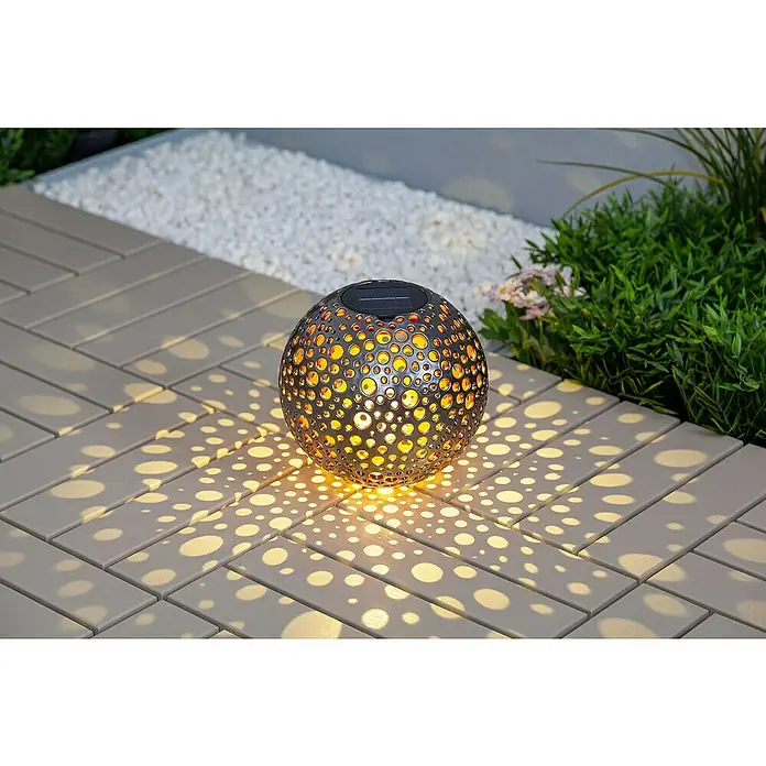 BAUHAUS Solar-Dekoleuchte Punkte - 0,06 W, L x B x H: 20 x 20 x 20 cm, Silber-Metallic/ Kupfergold, IP44 - Solarleuchte in Kugelform mit Muster, die warmes Licht auf einem hellen Steinweg erzeugt.