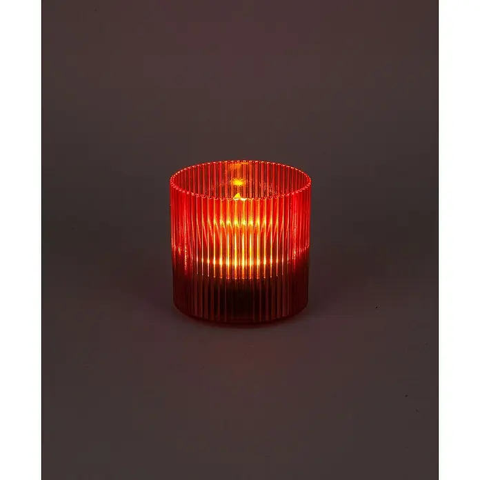 BAUHAUS Solar-Dekoleuchte Teelicht - 0,6 W, Rot, IP44 - Nahaufnahme einer geriffelten roten Glas-Kerzenhalter mit warmem Licht, ideal für stimmungsvolle Beleuchtung.