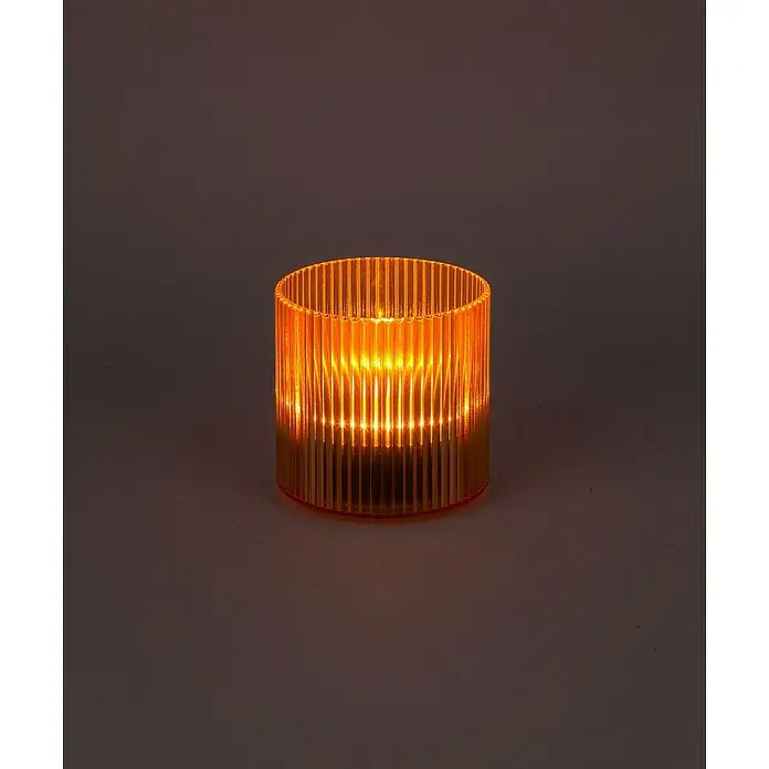 BAUHAUS Solar-Dekoleuchte Teelicht - 0,6 W, Mango, IP44 - Eine goldene, gerippte Glas-Teelichthalter leuchtet hell und erzeugt ein warmes, stimmungsvolles Licht auf einer ebenen Fläche.
