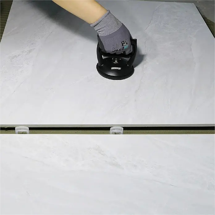 Bihui Saugheber SCSB4 - Tragkraft: 40 kg - Schwarzer Doppelgriff-Saugnapf-Fliesenheber, von einer behandschuhten Hand auf einer weißen Fliese zur Installation verwendet.